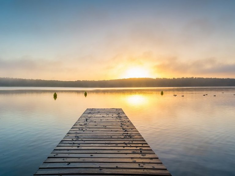 naturbild-seestimmung mit steg-sonnenspiegelung auf dem wasser